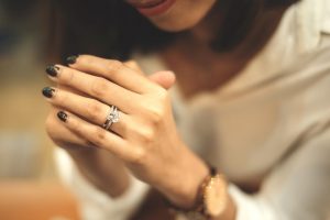 A close-up of a woman's hand wearing a diamond engagement ring and wedding ring