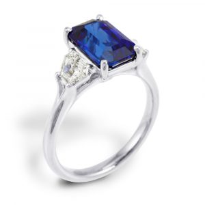 A platinum 3.32ct emerald cut sapphire and 0.62ct diamond three stone ring