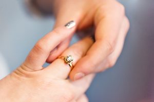 A diamond engagement ring being placed on a women's finger by a man