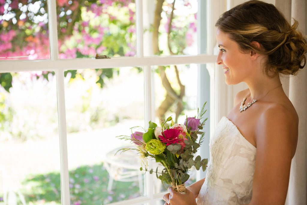 A beautiful German bride wearing an off-the-shoulder dress and holding a floral bouquet