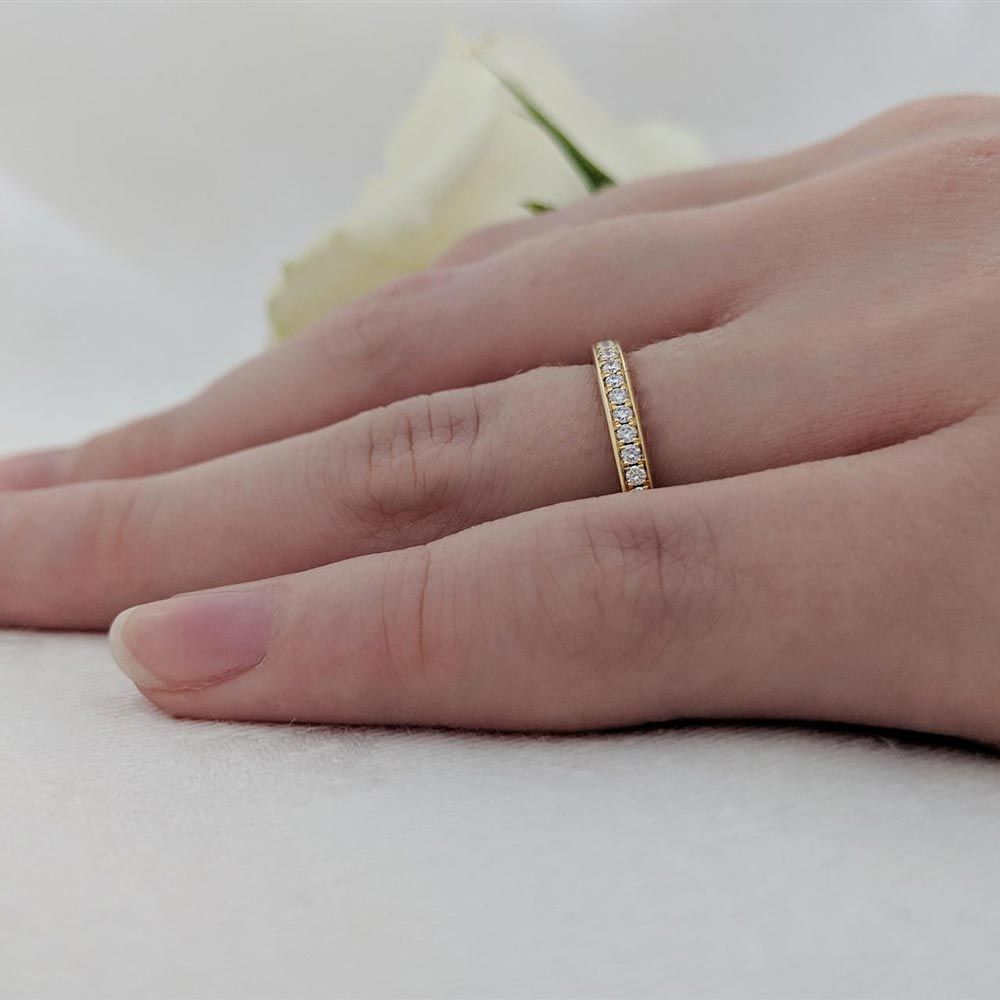 The 18ct yellow gold Memoire 0.15ct round brilliant cut diamond eternity ring worn on a finger