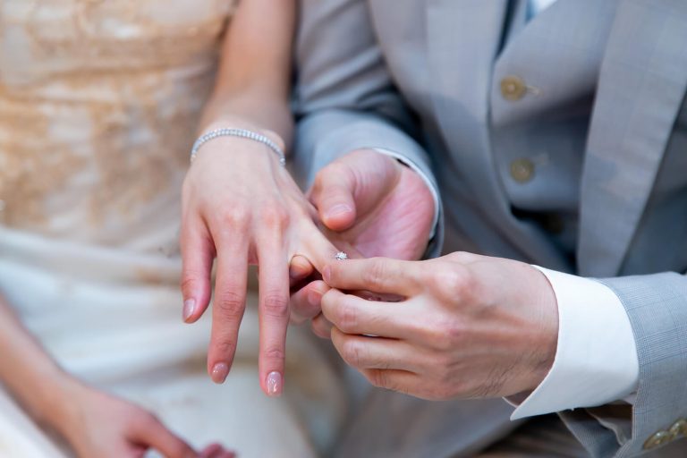 A groom placing a ring on his bride's finger on their wedding day