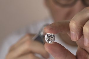 A jeweller inspecting and grading a loose diamond with a loupe. How to tell if a diamond is real.