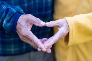 Close-up of the elderly couple showing making a heart with fingers. Concept of aged people and love. Diamond wedding anniversary.