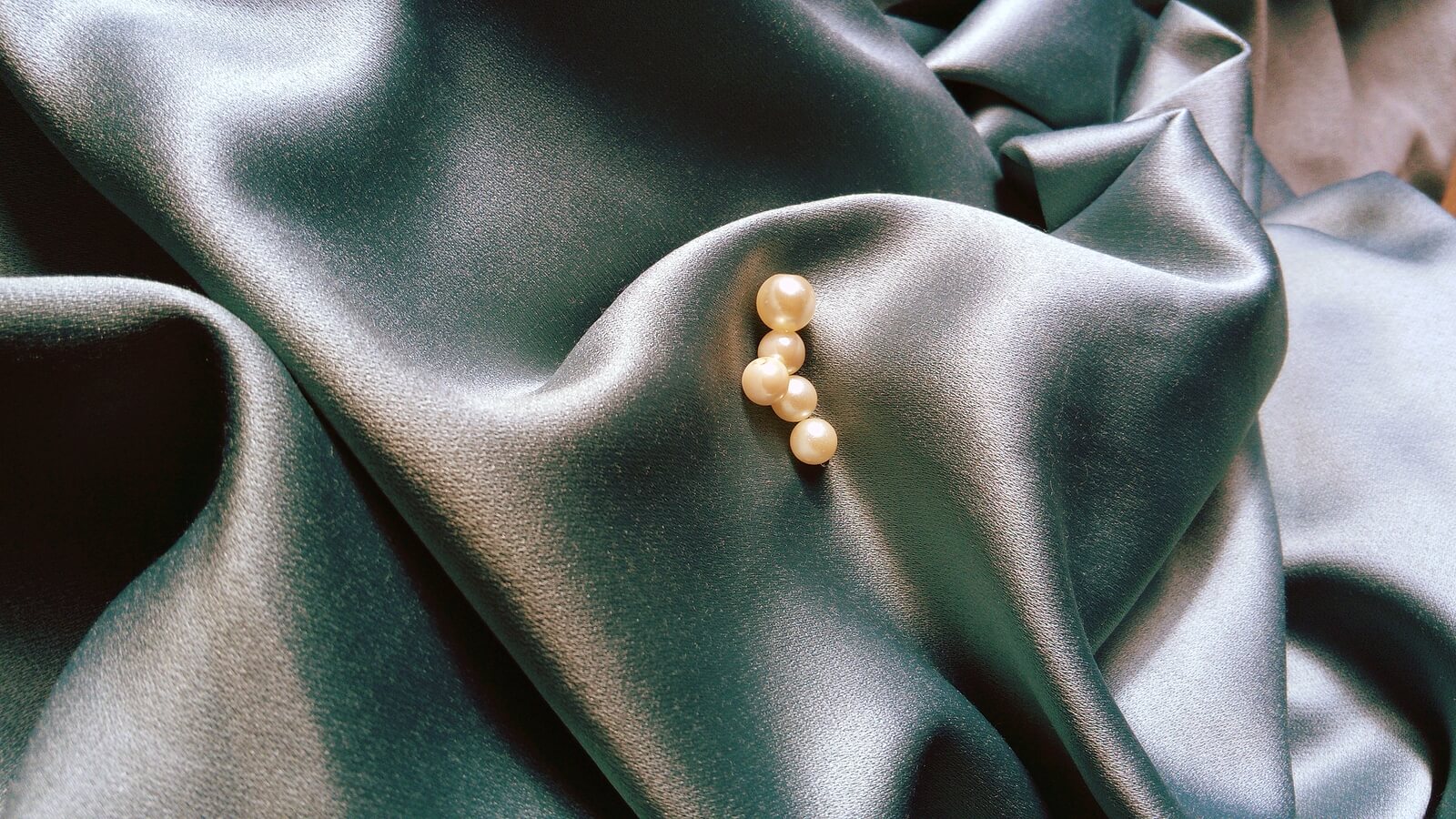 beautiful pearl beads on crumpled gray silk fabric with a greenish tint. Texture of satin or natural silk. Womens jewelry